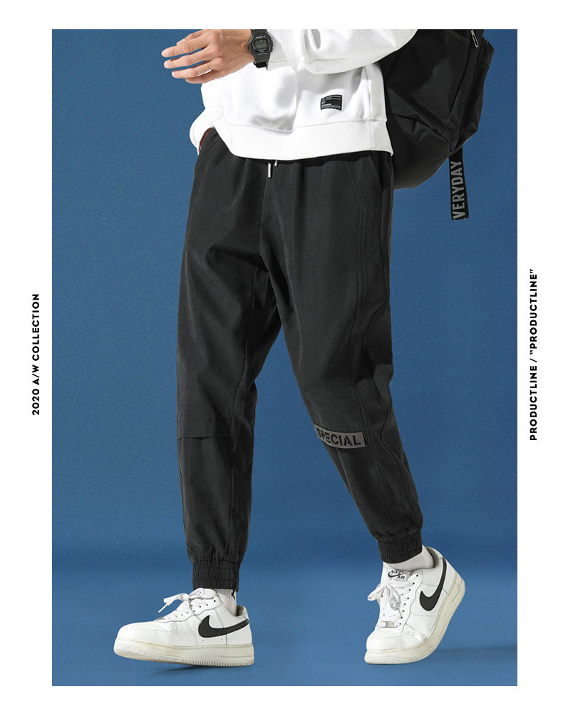 Men's reflective athleisure pants in black with adjustable drawstring and tapered fit