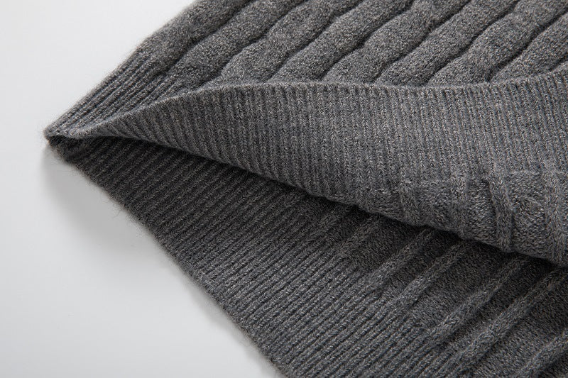 Close-up of a grey long sleeve cable knit pullover showcasing its textured fabric and ribbed hem