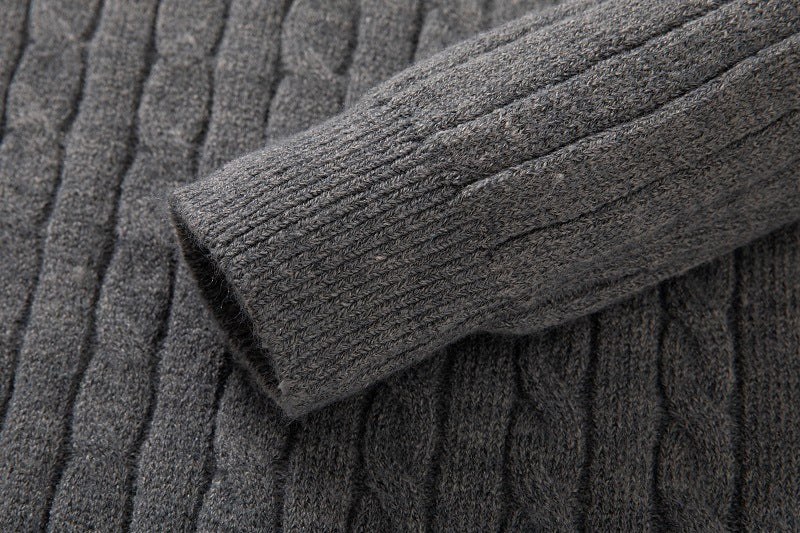 Close-up of gray long sleeve cable knit pullover showcasing textured fabric and detailed stitching
