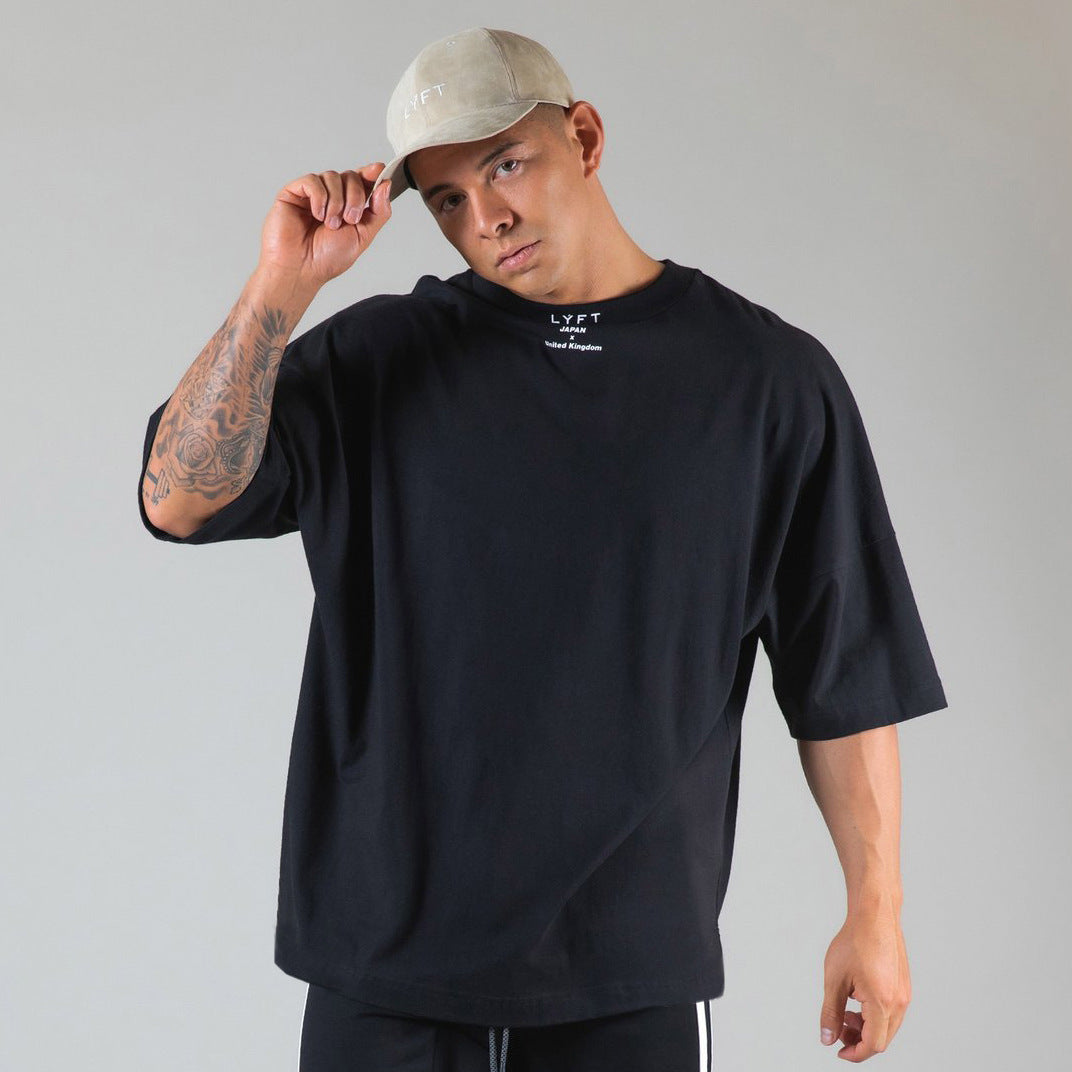 Model wearing a black round neck athleisure shirt with a relaxed fit and casual style