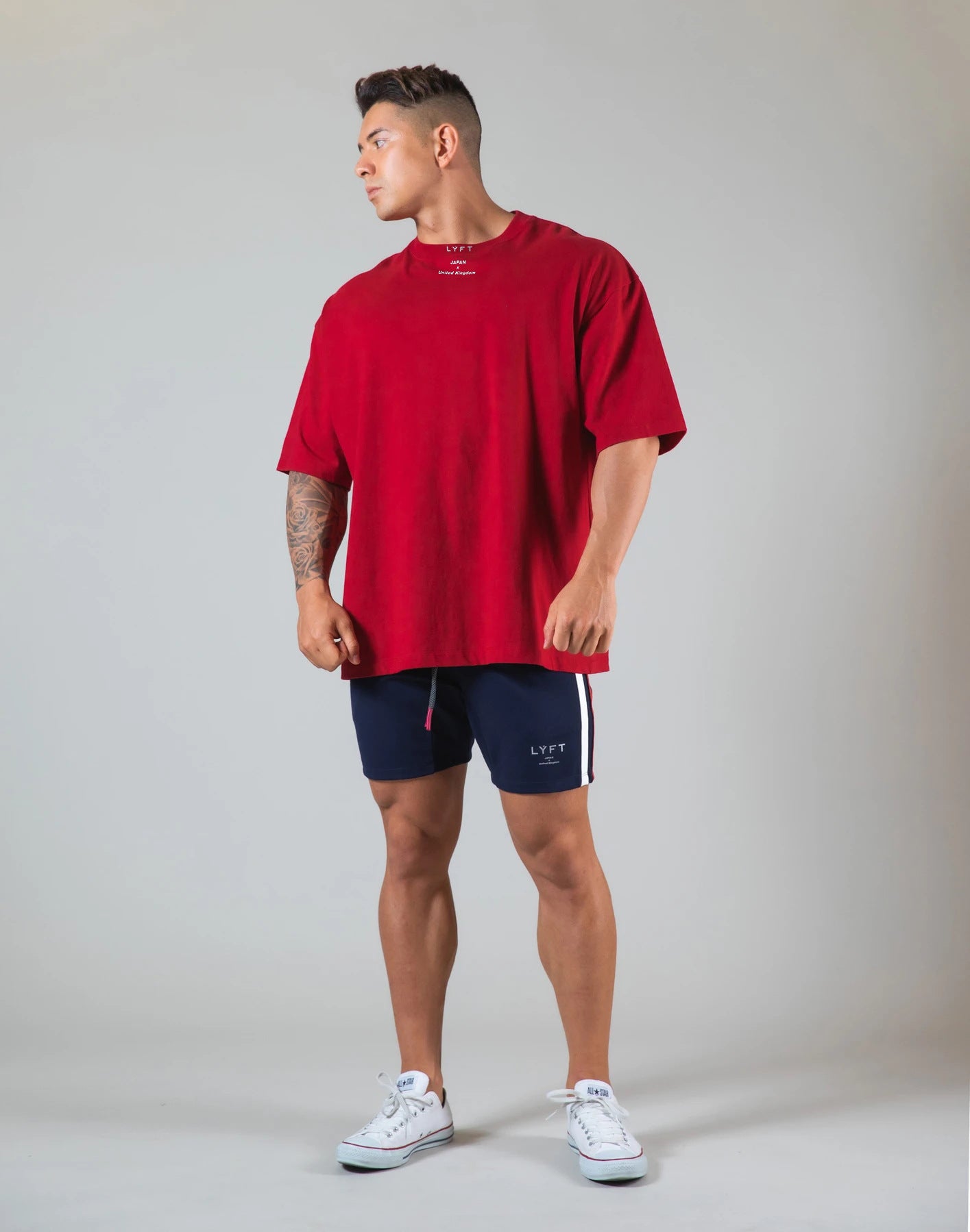 Model wearing a red round neck athleisure shirt paired with navy shorts for a casual look